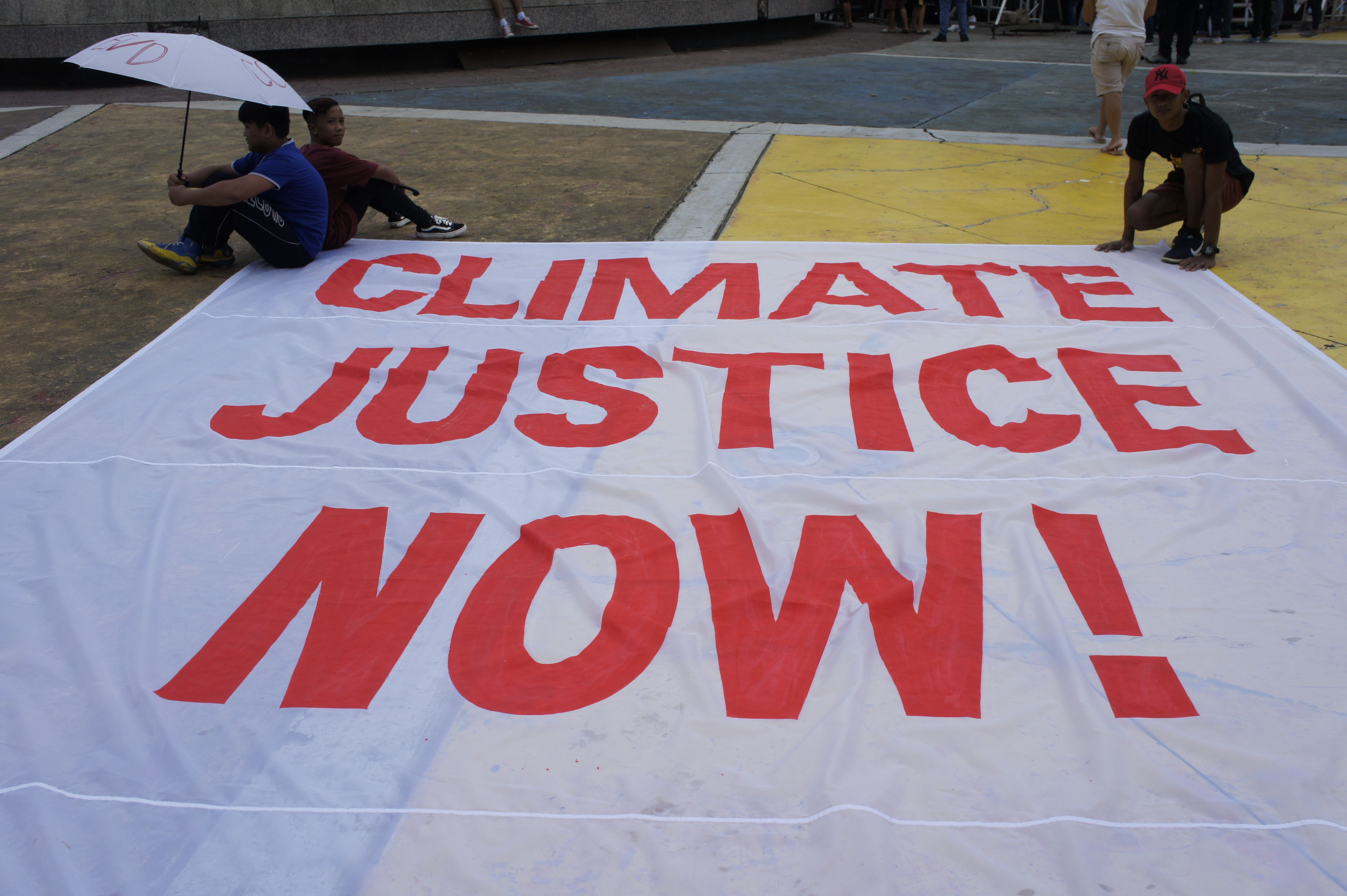 Large Climate Justice Now banner at an environmental demonstration