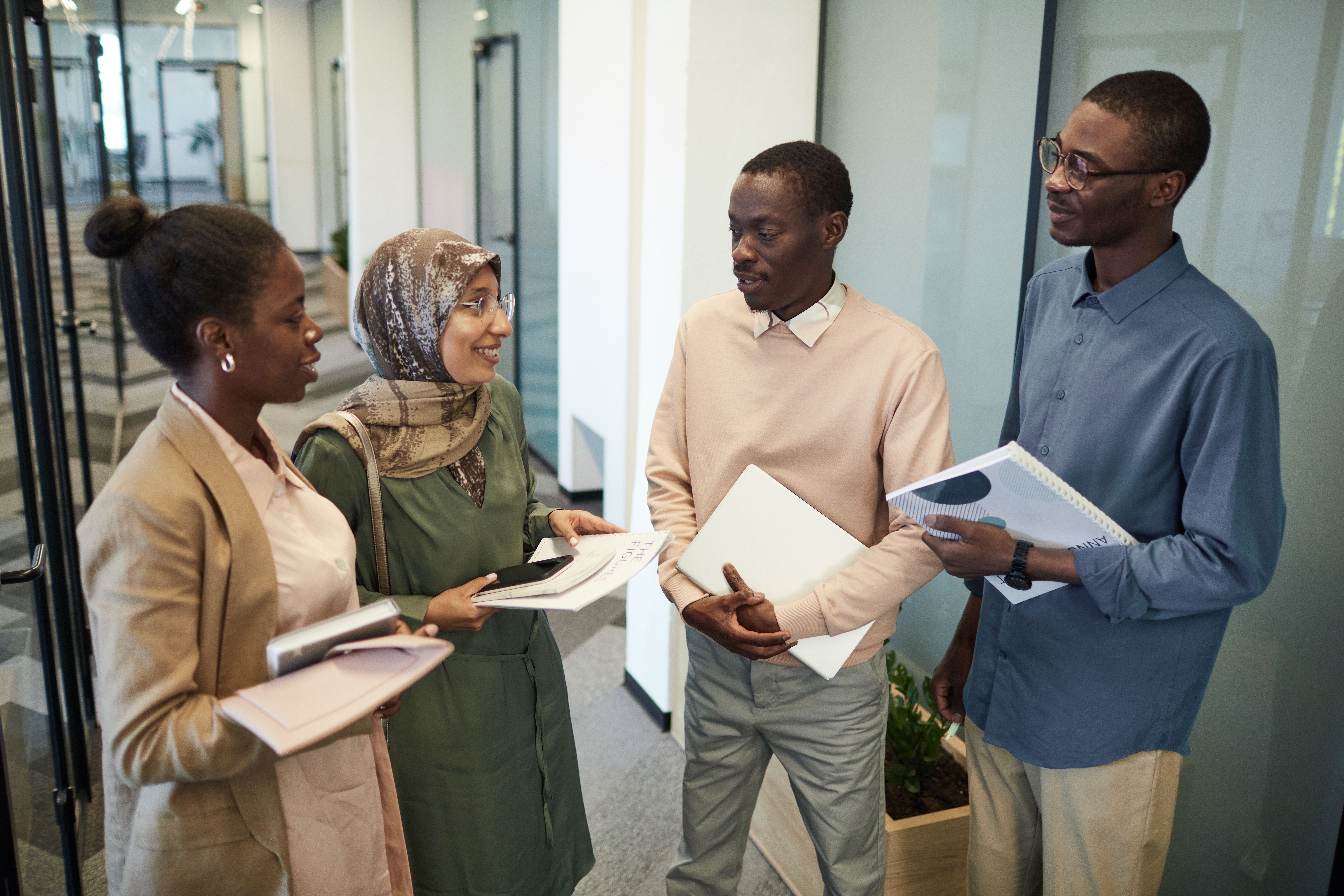 Multicultural coworkers discussing work materials during an office meeting.