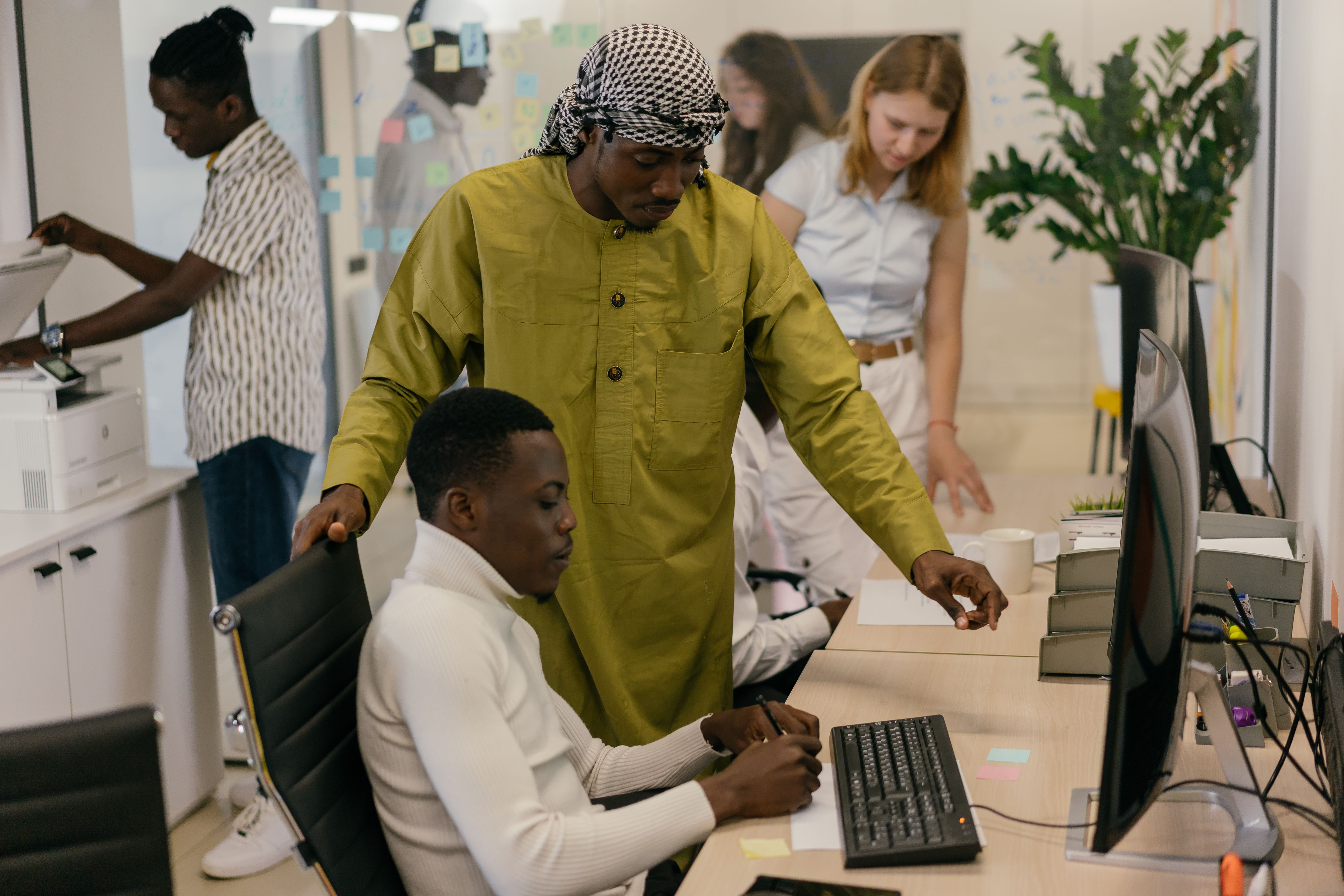 Multicultural colleagues working together in a modern office with computers and documents.