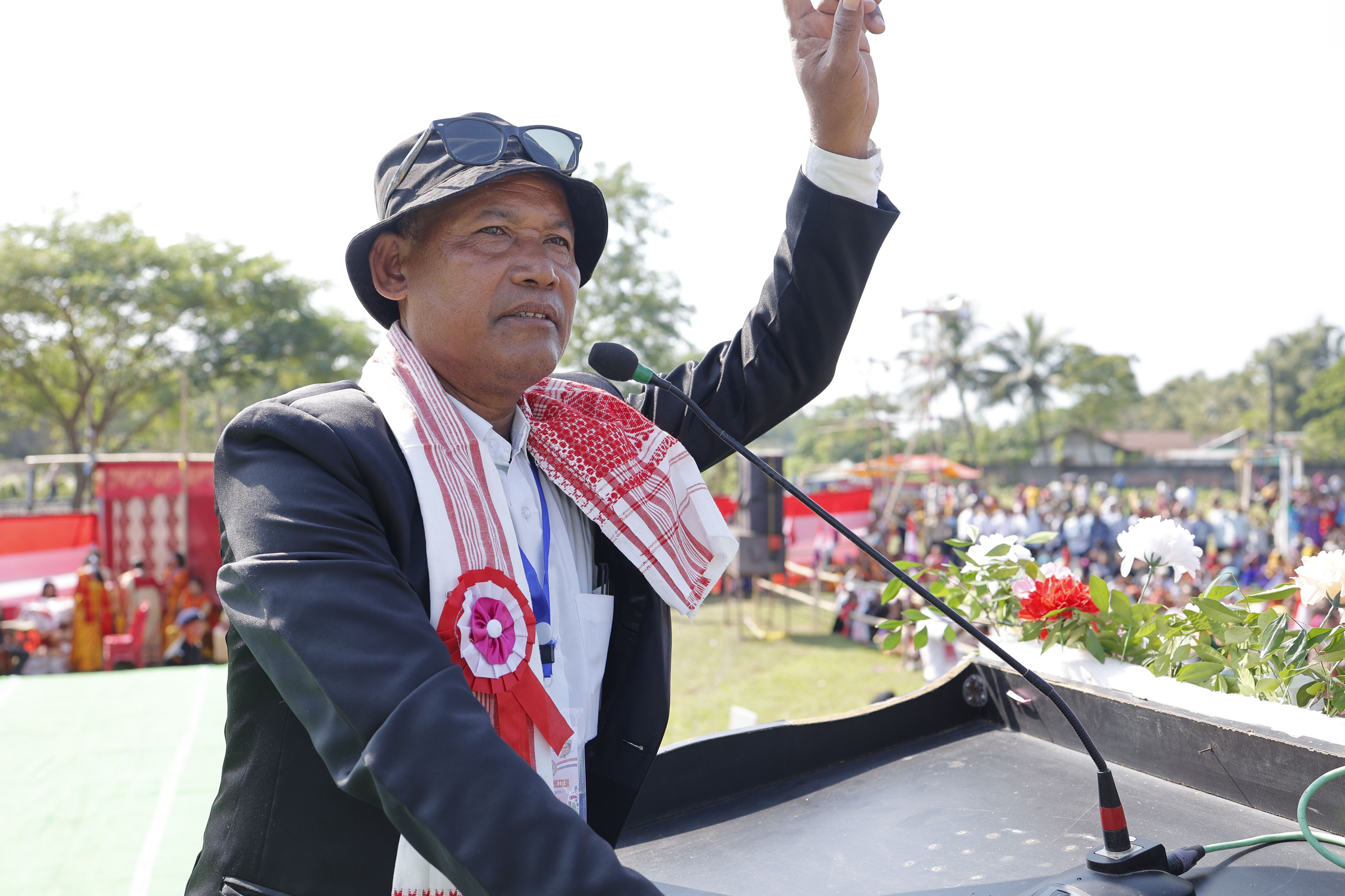 A man giving a speech at an outdoor rally, gesturing with his hand