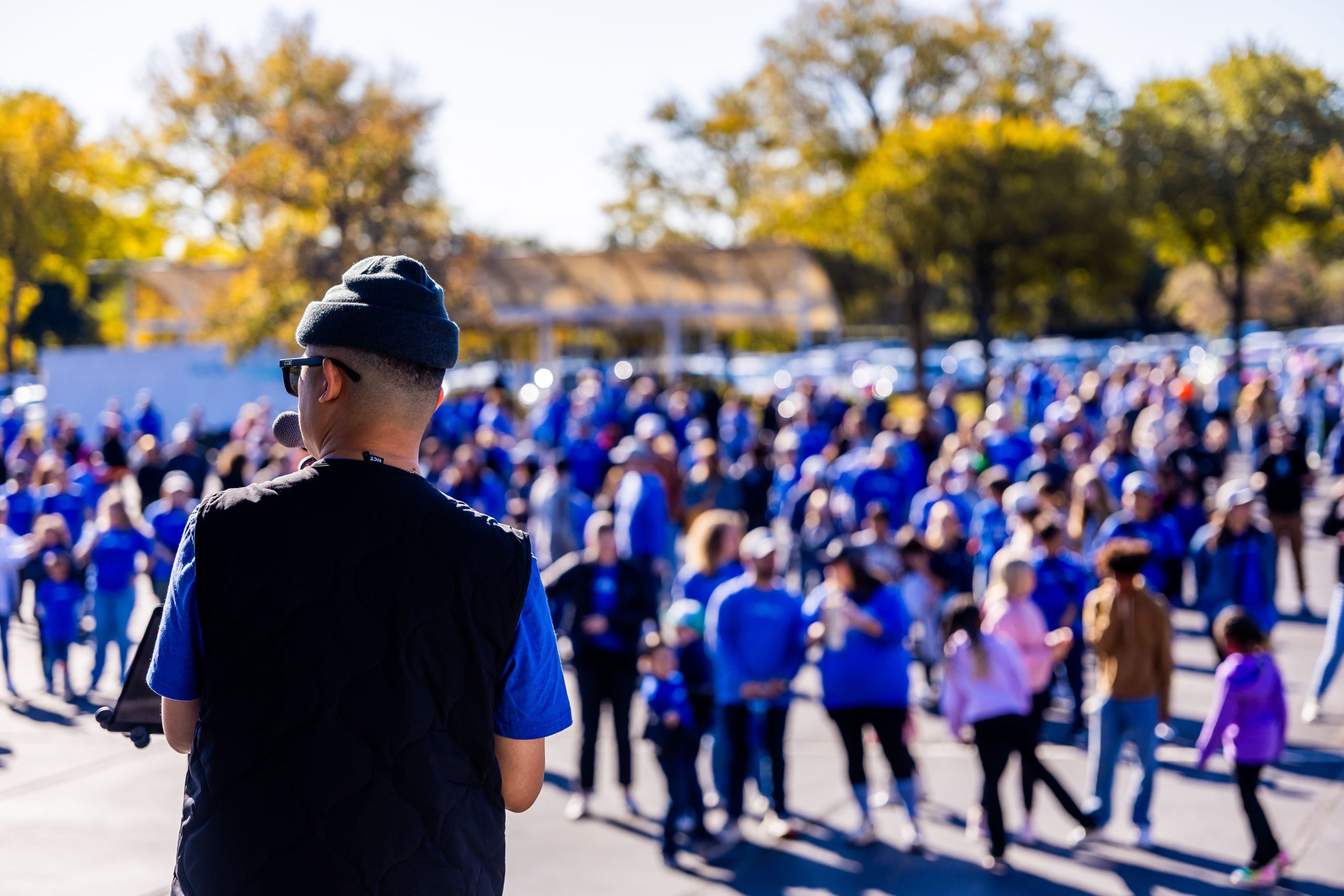 A speaker addresses a large crowd gathered outdoors at a community event