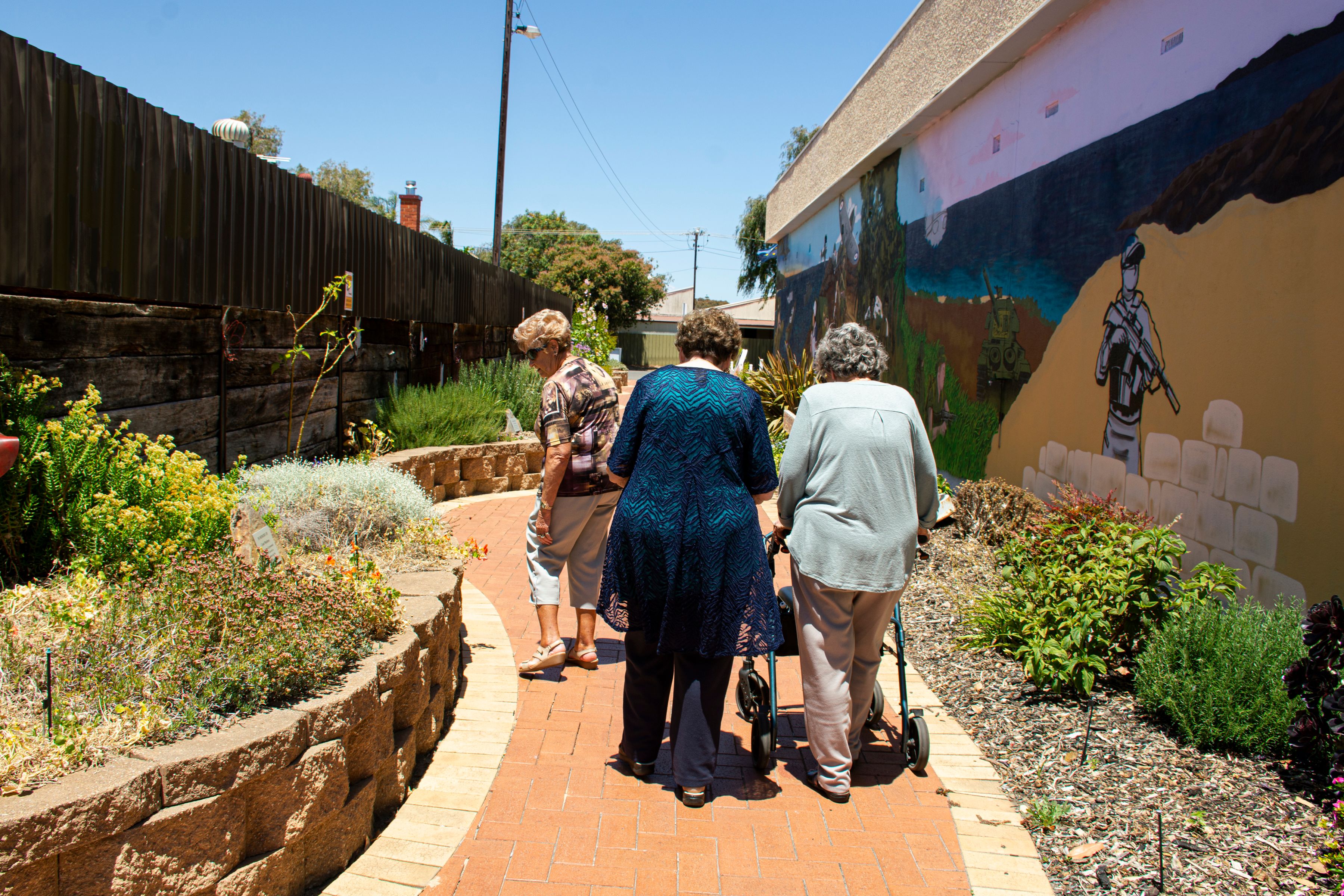 Three older women walk together outdoors, enjoying friendship and community.