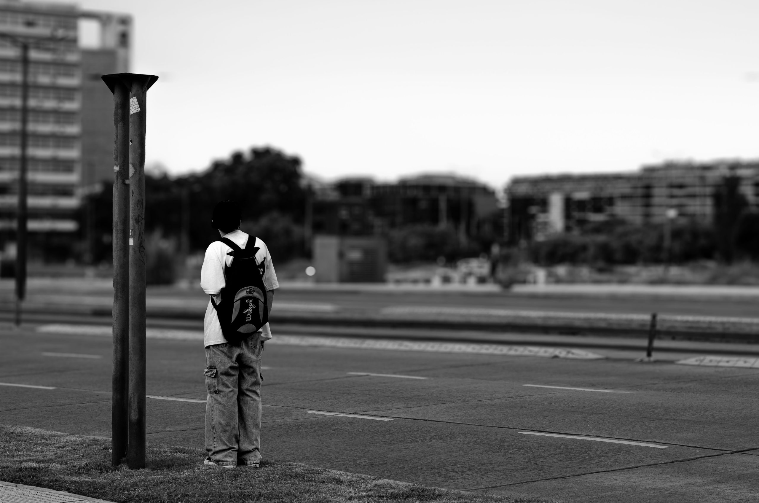 A person stands alone on a busy-looking urban street, illustrating the isolation that can persist amid city life.